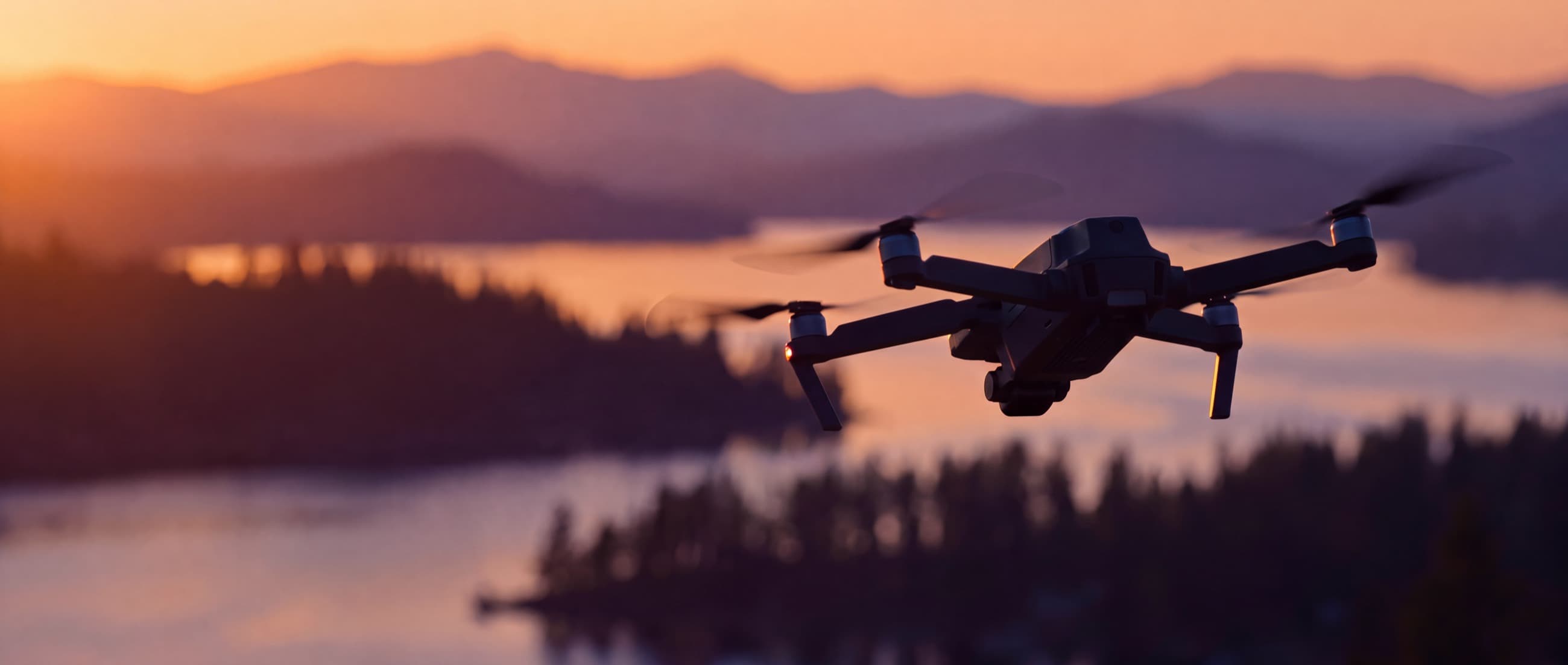 A camera drone in flight at golden hour above a forested north Idaho lake