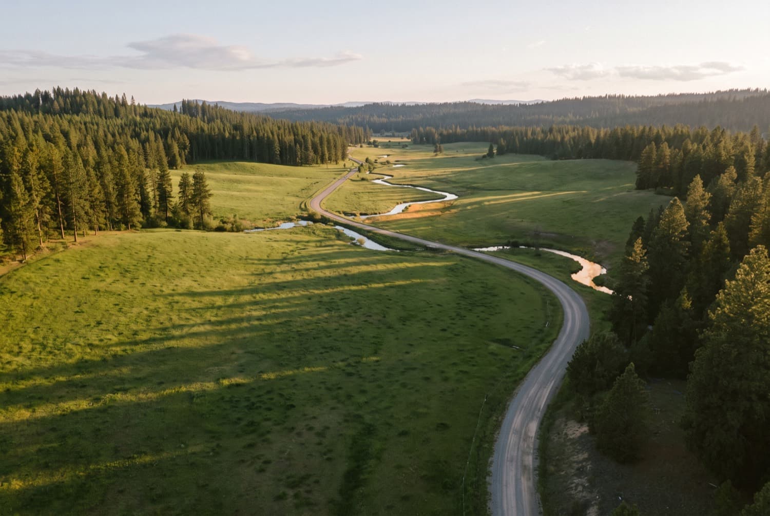 Aerial view of open acreage, a creek and an access road